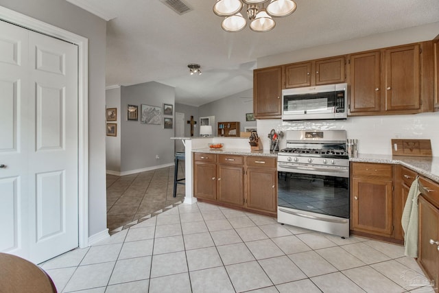 kitchen with appliances with stainless steel finishes, brown cabinetry, and visible vents