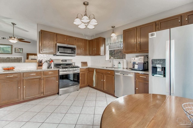 kitchen with hanging light fixtures, appliances with stainless steel finishes, a sink, and brown cabinets