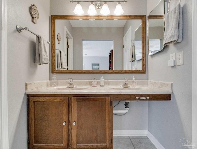 full bath with double vanity, a sink, baseboards, and tile patterned floors