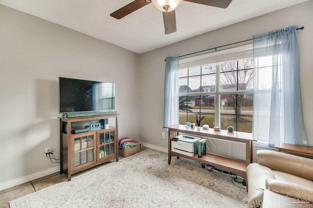 living area with ceiling fan, baseboards, and tile patterned floors