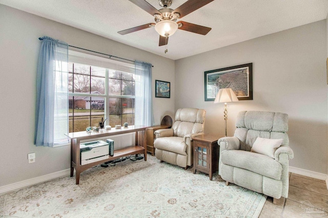 sitting room featuring ceiling fan, baseboards, and a textured ceiling