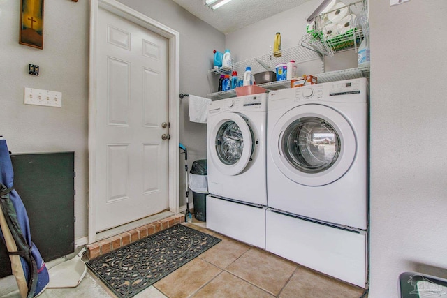 clothes washing area featuring laundry area, tile patterned flooring, separate washer and dryer, and a textured ceiling