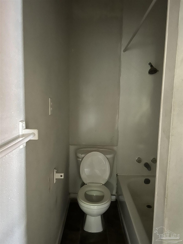 bathroom featuring tile patterned flooring, a washtub, and toilet