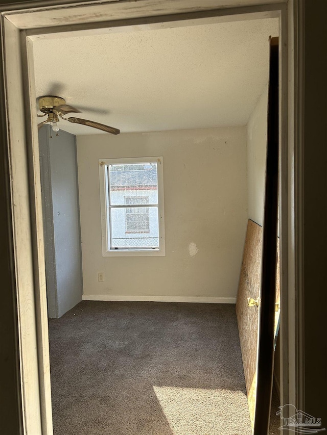 empty room featuring ceiling fan, carpet floors, and a textured ceiling