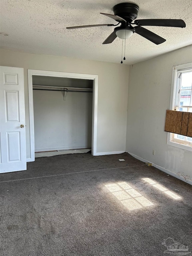 unfurnished bedroom featuring ceiling fan, a closet, a textured ceiling, and dark colored carpet