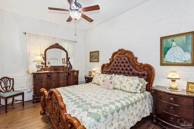 bedroom featuring hardwood / wood-style flooring, ceiling fan, and brick wall