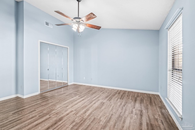 unfurnished bedroom with hardwood / wood-style floors, a closet, vaulted ceiling, and ceiling fan