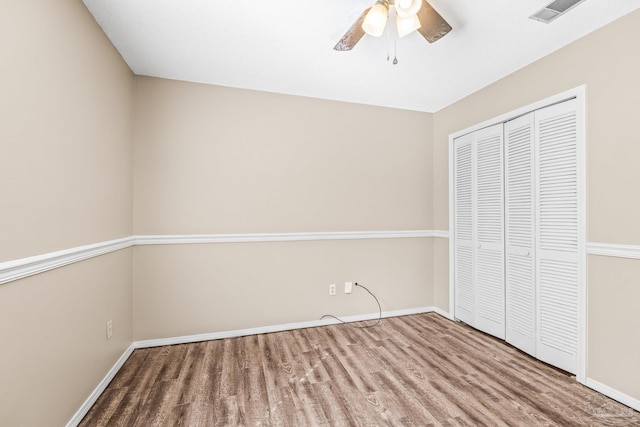 unfurnished bedroom with hardwood / wood-style flooring, ceiling fan, and a closet