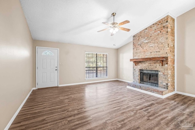 unfurnished living room with a textured ceiling, ceiling fan, a fireplace, hardwood / wood-style floors, and lofted ceiling