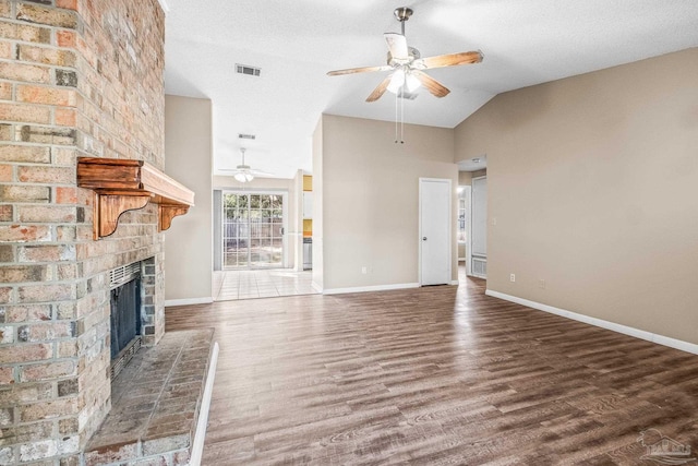 unfurnished living room with lofted ceiling, ceiling fan, a textured ceiling, a fireplace, and dark hardwood / wood-style flooring