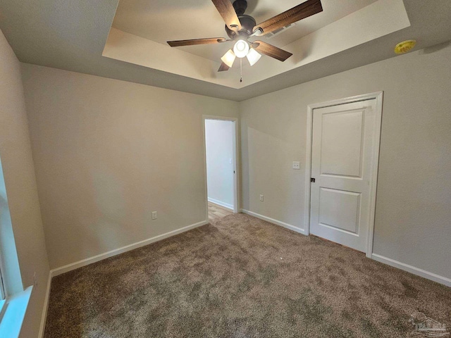 unfurnished room with ceiling fan, a raised ceiling, and carpet floors