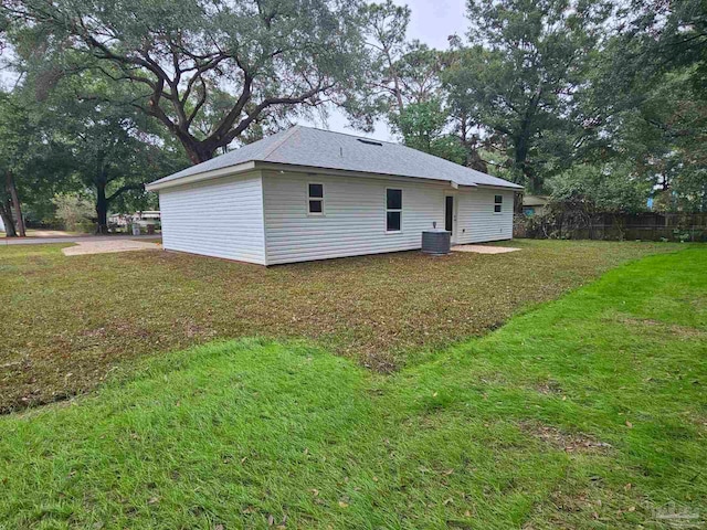 back of house with central AC unit and a lawn