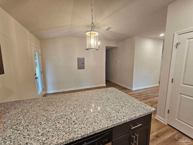 kitchen with electric panel, hardwood / wood-style floors, dark brown cabinetry, hanging light fixtures, and light stone countertops