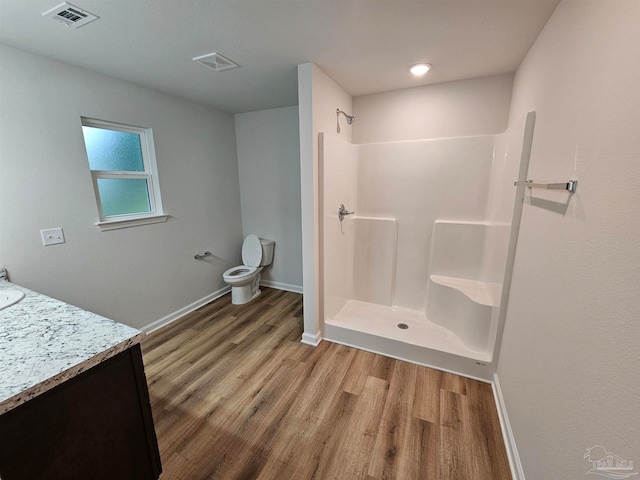 bathroom with walk in shower, hardwood / wood-style floors, vanity, and toilet