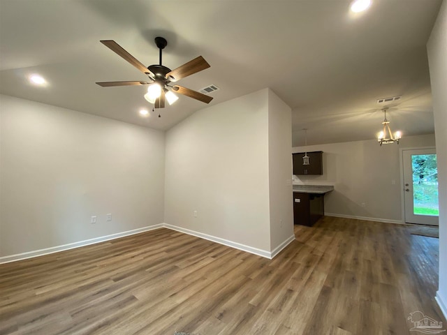 unfurnished room with dark wood-type flooring, lofted ceiling, and ceiling fan with notable chandelier