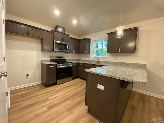 kitchen featuring pendant lighting, appliances with stainless steel finishes, light hardwood / wood-style floors, and light stone counters