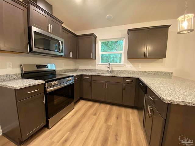 kitchen with stainless steel appliances, dark brown cabinetry, pendant lighting, sink, and light hardwood / wood-style flooring