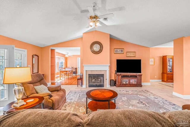 living room featuring a fireplace, a textured ceiling, vaulted ceiling, and ceiling fan