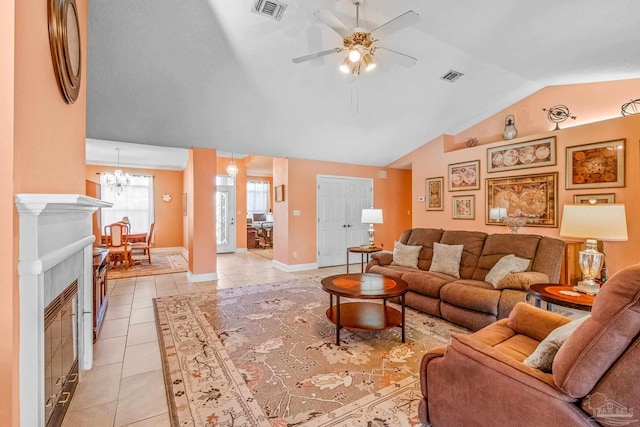 tiled living room featuring a tile fireplace, ceiling fan with notable chandelier, and lofted ceiling