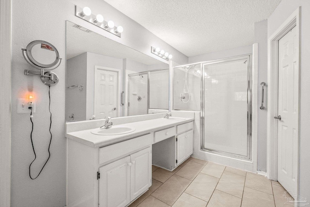 bathroom with tile patterned flooring, vanity, a textured ceiling, and walk in shower