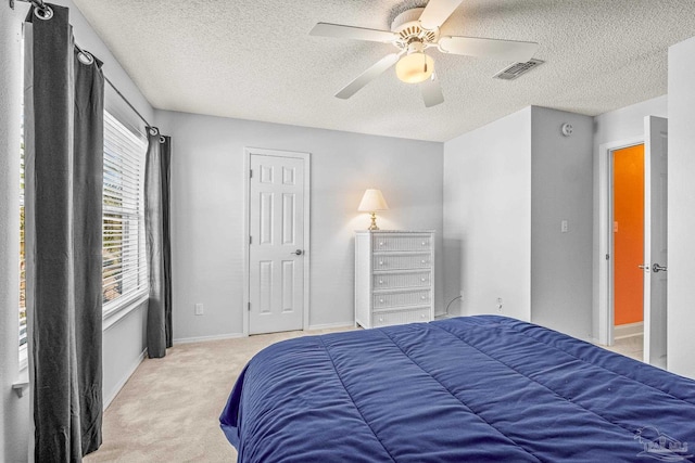 carpeted bedroom featuring ceiling fan and a textured ceiling