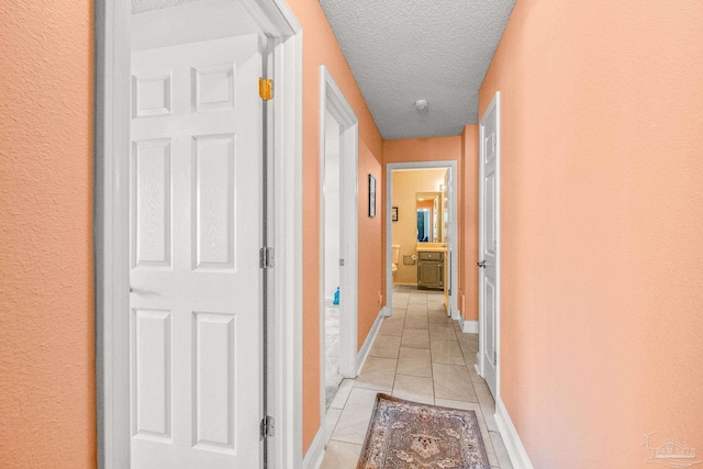 corridor featuring light tile patterned floors and a textured ceiling