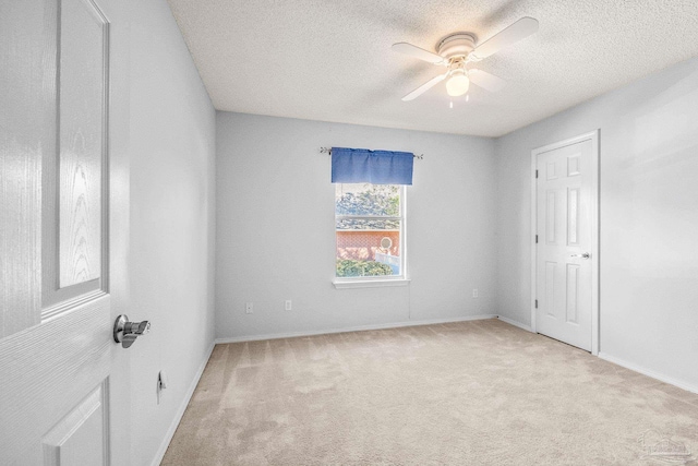 unfurnished room featuring a textured ceiling, light colored carpet, and ceiling fan