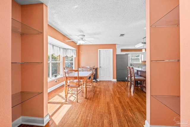 dining space featuring ceiling fan, wood-type flooring, and a textured ceiling