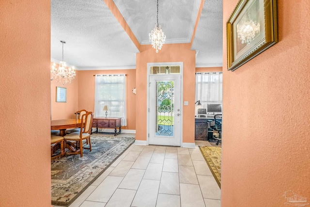 foyer entrance featuring plenty of natural light, crown molding, a textured ceiling, and a chandelier