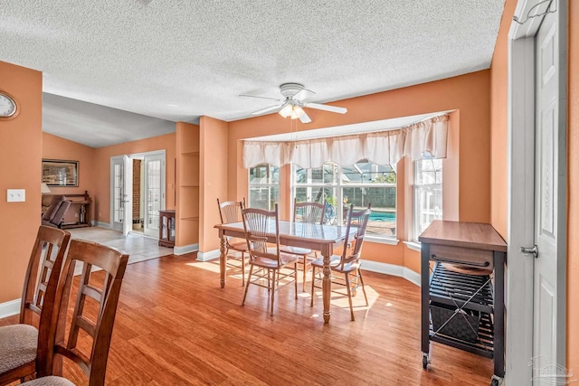 dining room featuring light wood-type flooring, a textured ceiling, beverage cooler, ceiling fan, and lofted ceiling