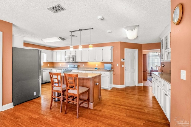 kitchen featuring a center island, white cabinetry, stainless steel appliances, and light hardwood / wood-style flooring