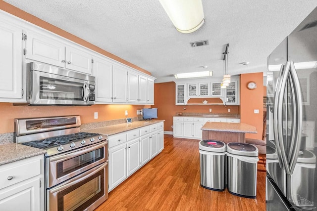 kitchen featuring white cabinets, appliances with stainless steel finishes, and light hardwood / wood-style flooring