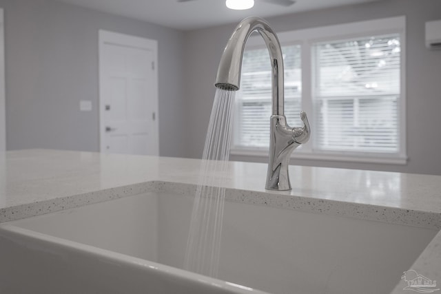 details with a wall mounted AC, light stone counters, and sink