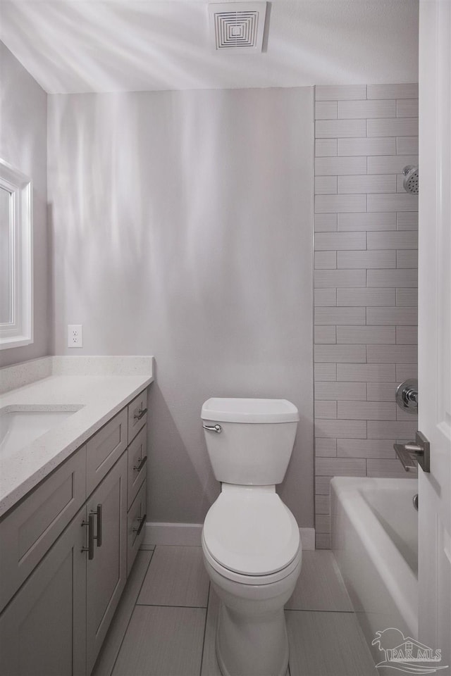 full bathroom with tiled shower / bath, tile patterned flooring, vanity, and toilet