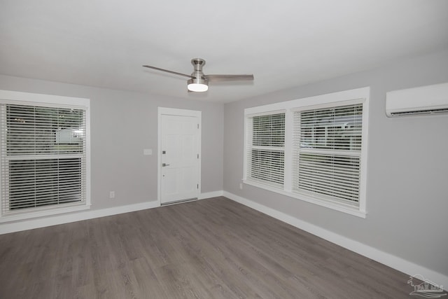 unfurnished room with wood-type flooring, an AC wall unit, and ceiling fan