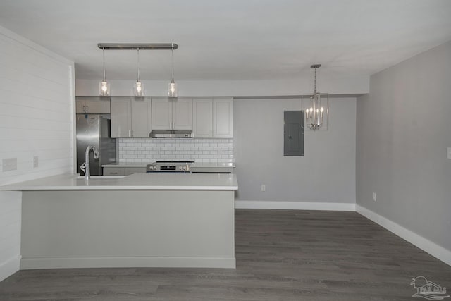 kitchen featuring dark hardwood / wood-style floors, backsplash, electric panel, pendant lighting, and appliances with stainless steel finishes