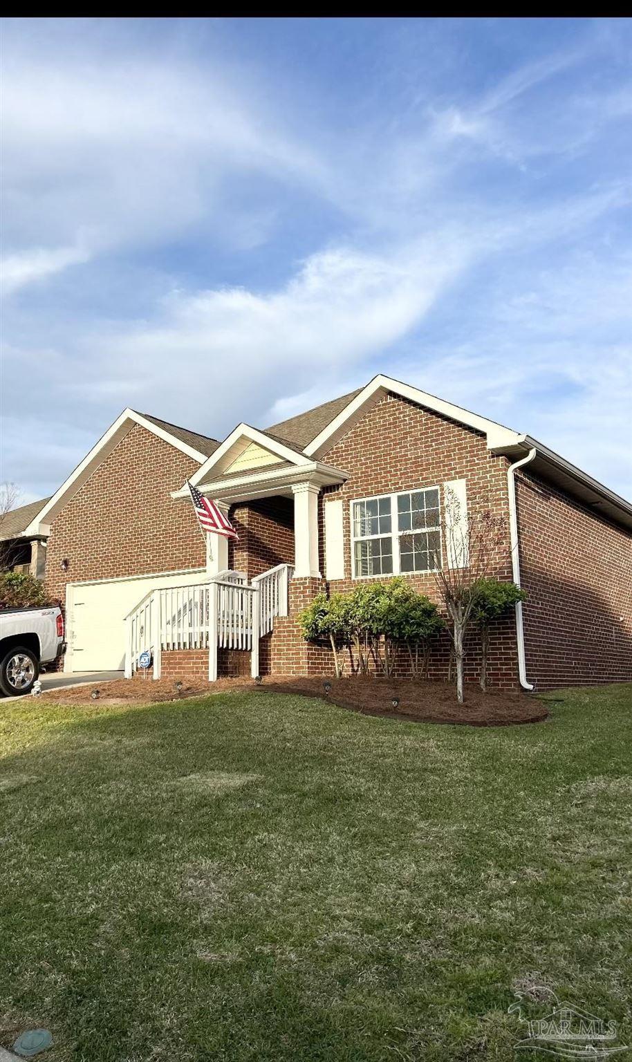 single story home featuring a front yard, a garage, and brick siding