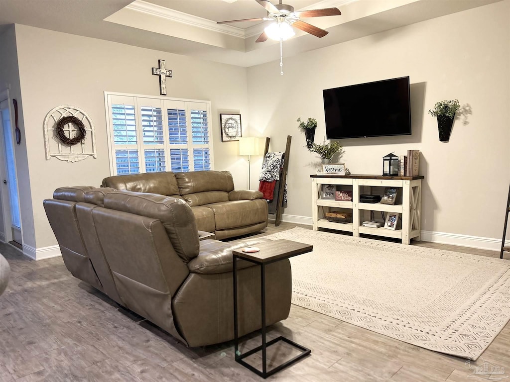 living room featuring ceiling fan, crown molding, a tray ceiling, and wood finished floors