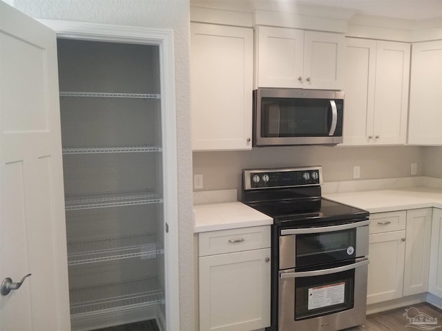 kitchen featuring appliances with stainless steel finishes, dark wood-type flooring, and white cabinetry