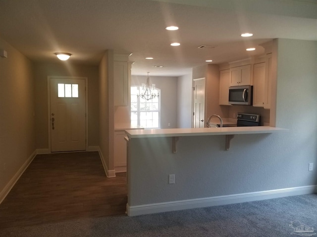 kitchen with hanging light fixtures, kitchen peninsula, white cabinetry, a breakfast bar area, and dark hardwood / wood-style flooring