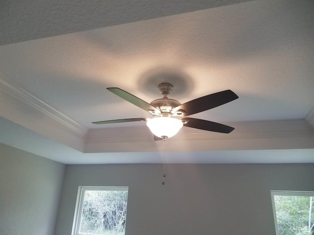 details with a textured ceiling, a raised ceiling, crown molding, and ceiling fan