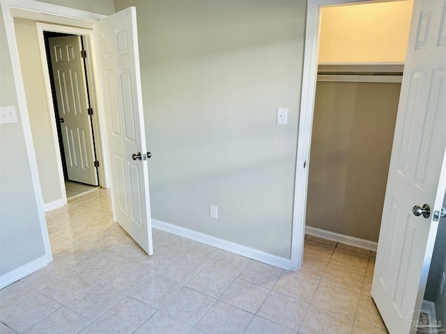 unfurnished bedroom featuring light tile patterned floors and a closet