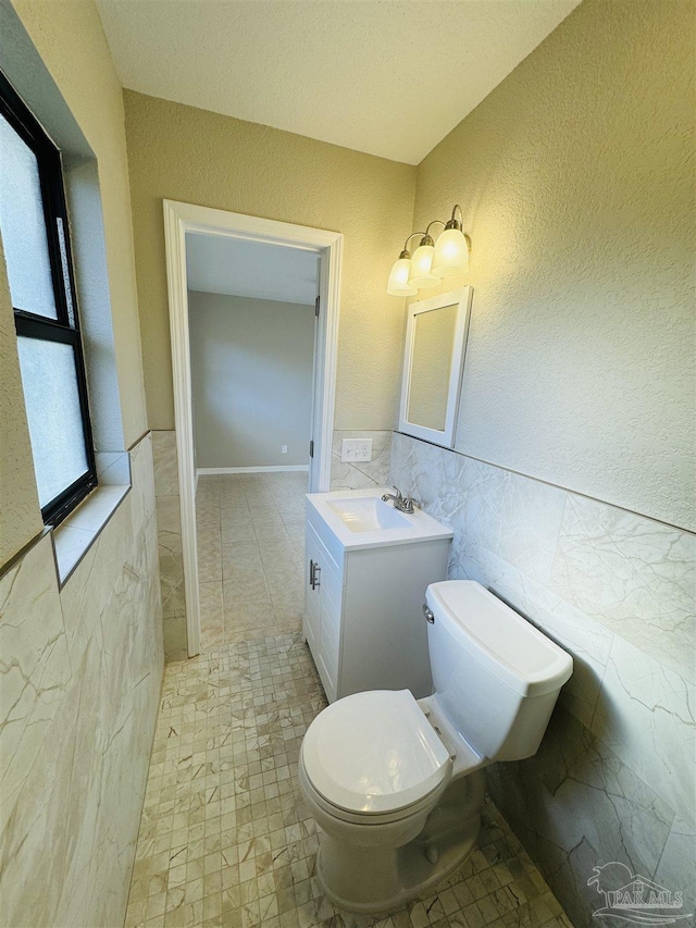 bathroom with vanity, tile walls, and toilet