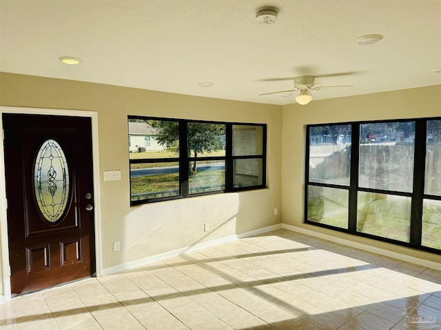 tiled entrance foyer featuring ceiling fan and a healthy amount of sunlight