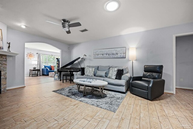 living room featuring a fireplace, ceiling fan, and light hardwood / wood-style flooring