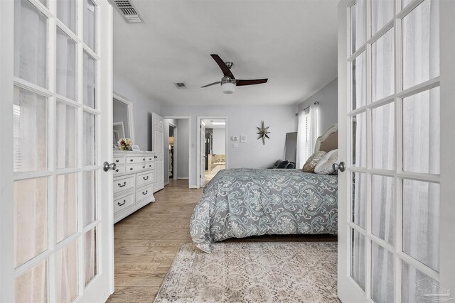 bedroom featuring light wood-type flooring, ensuite bath, and ceiling fan