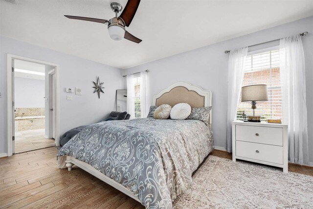 bedroom featuring light wood-type flooring, ceiling fan, and ensuite bathroom