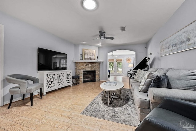 living room featuring ceiling fan, a fireplace, and light hardwood / wood-style flooring