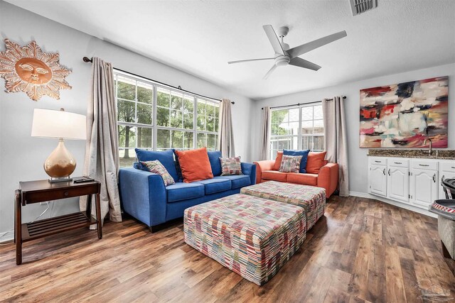 living room featuring a textured ceiling, sink, ceiling fan, and light hardwood / wood-style flooring