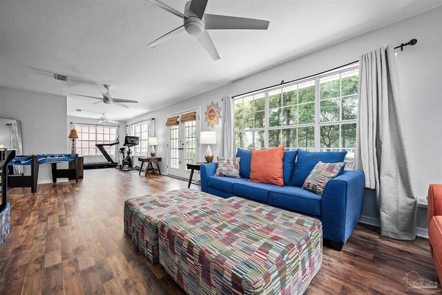 living room featuring ceiling fan, a textured ceiling, and dark wood-type flooring